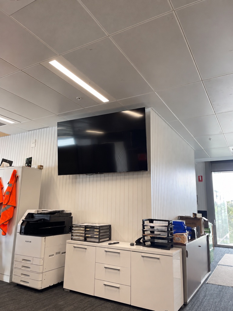 Office fit-out with linear LED ceiling lights and a wall-mounted TV