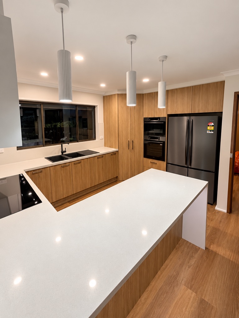 Kitchen with white pendant lights over a stone island bench