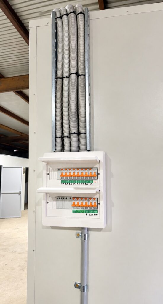New switchboard with circuit breakers and safety switches, fed by conduit on the wall of a commercial unit