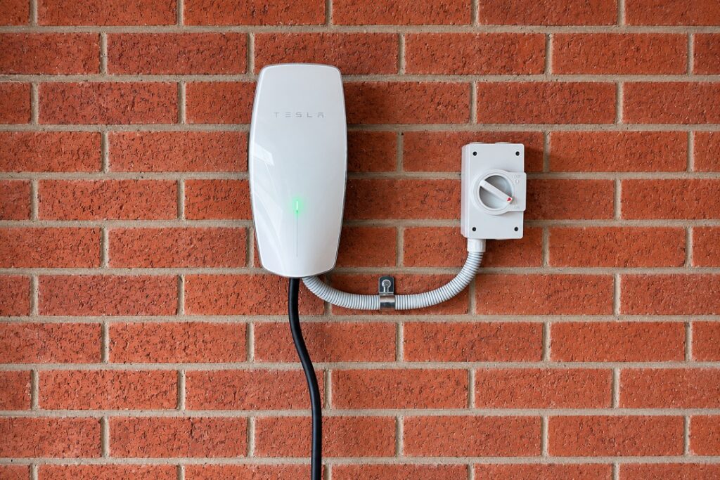 Wall-mounted EV charger with its own isolator on a brick wall
