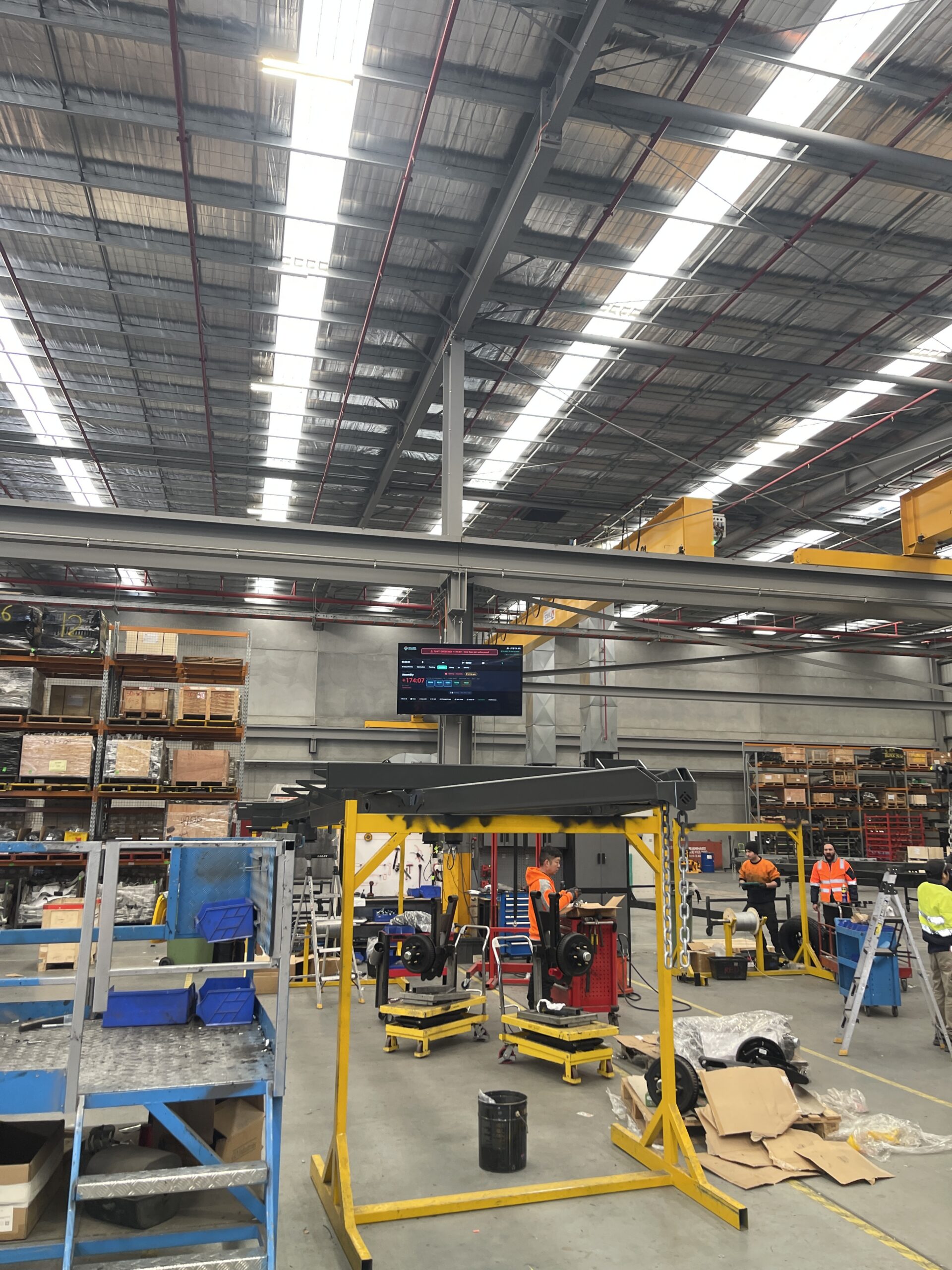 Workshop floor lit by rows of LED high-bay lights under a steel roof