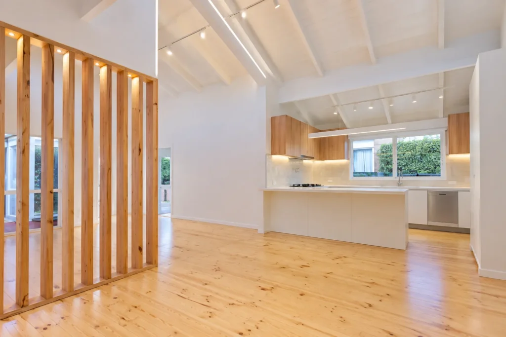Renovated open plan kitchen and living area with vertical timber divider, pine flooring and track lighting