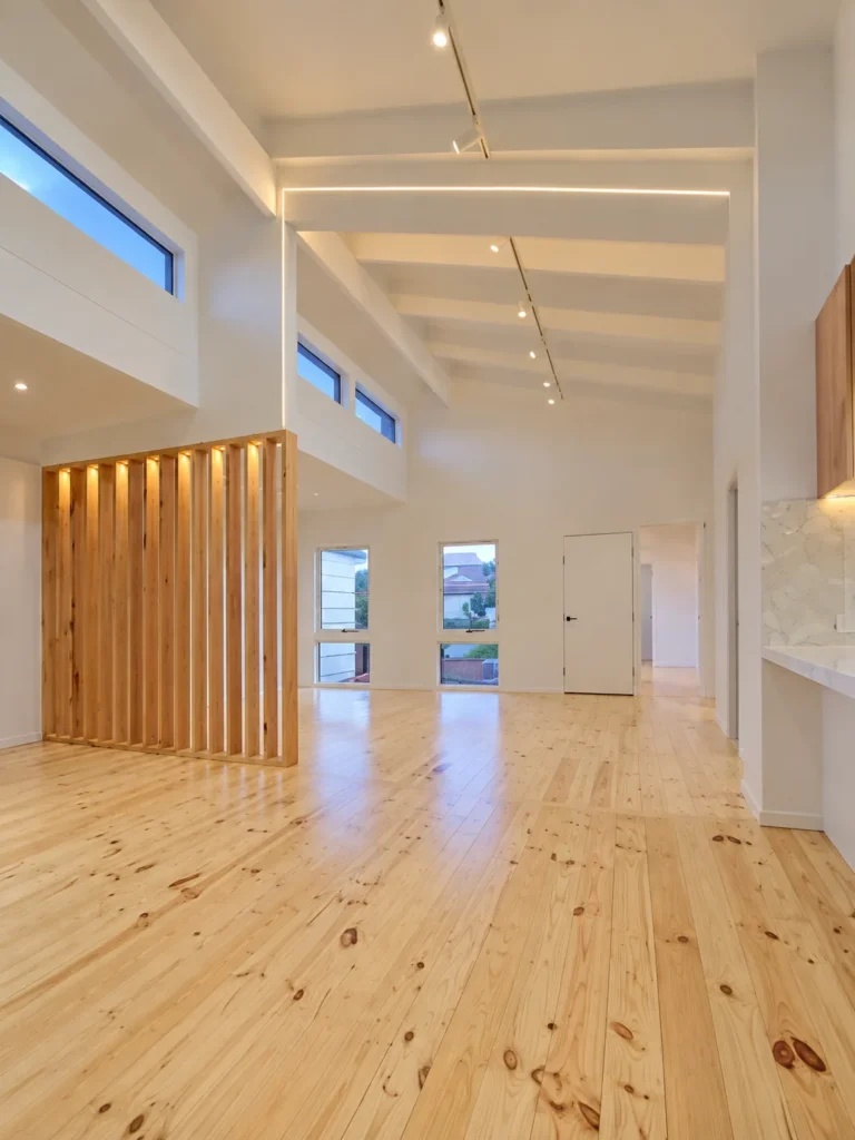 Renovated living area with raked ceiling, recessed LED strip lighting, track lighting and timber batten screen