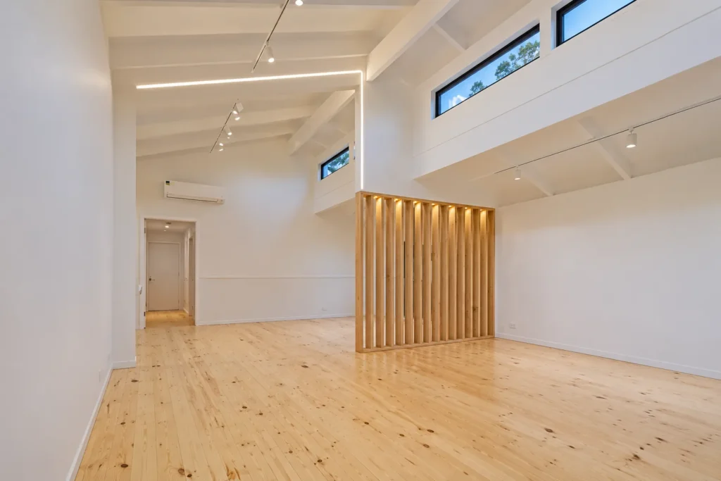 Renovated living space with clerestory windows, timber batten screen, track lighting and pine flooring