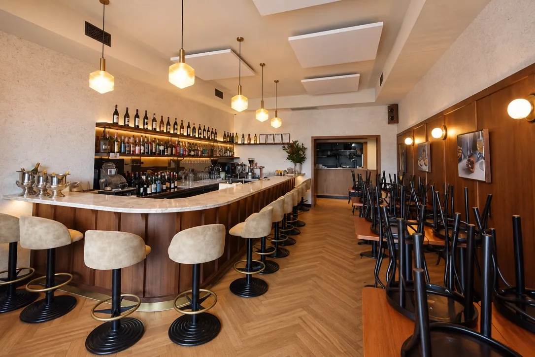 Bar fit out with curved timber panelling, a stone bar top, brass pendants and herringbone flooring