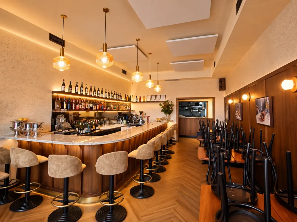 Hospitality venue with ribbed glass pendant lights over a curved bar, backlit bottle shelving and wall lights along the dining area