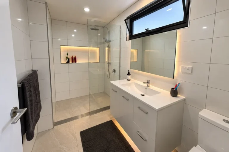Renovated bathroom with a walk in shower, linear drain, floating vanity and backlit mirror