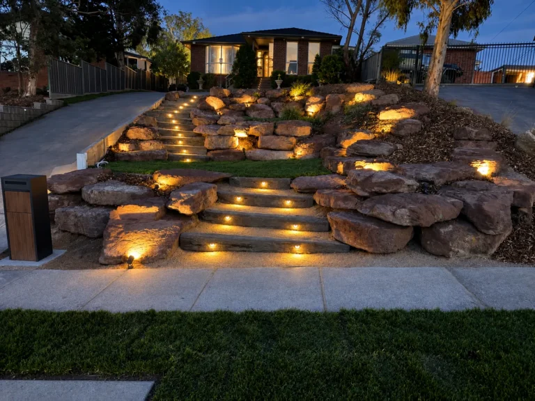 Sandstone garden steps and rockery lit with recessed step lights and spike lights at dusk