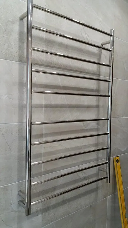 Heated towel rail installed on a tiled bathroom wall