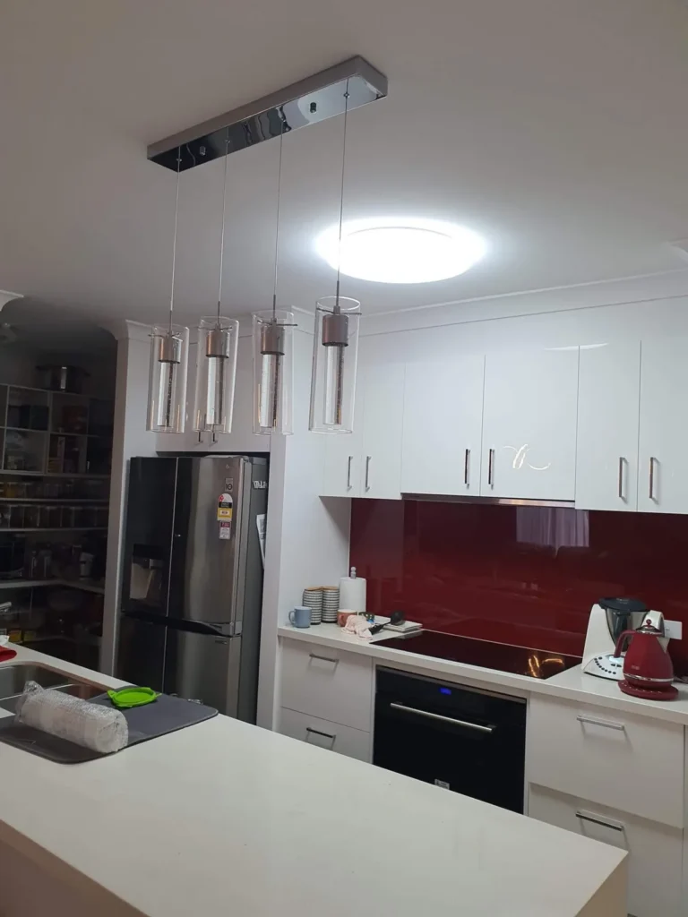 Kitchen with a row of glass pendant lights over the island bench and a round ceiling light