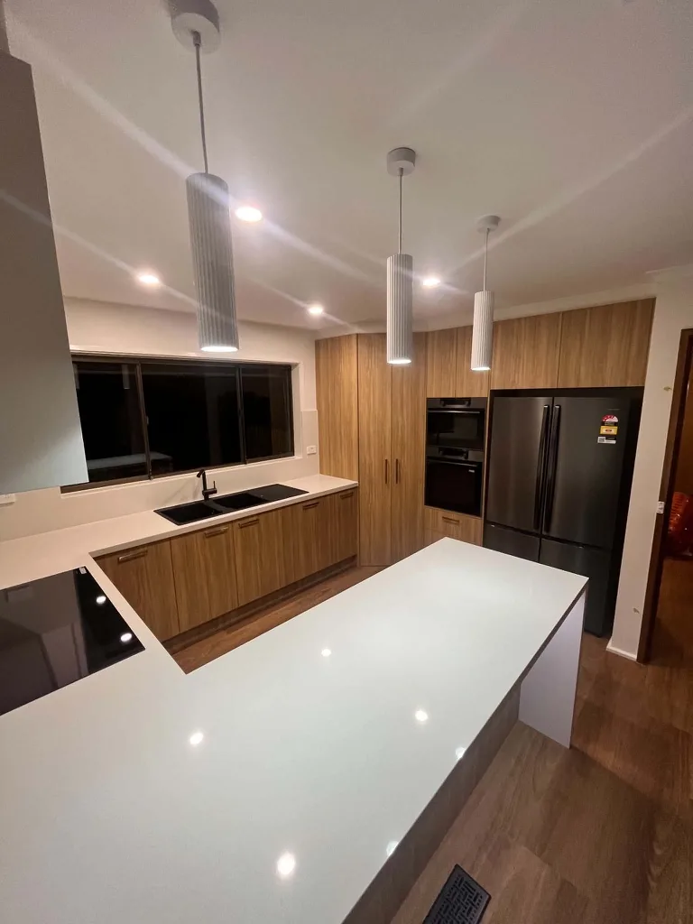 Renovated kitchen with pendant lighting over a stone island bench