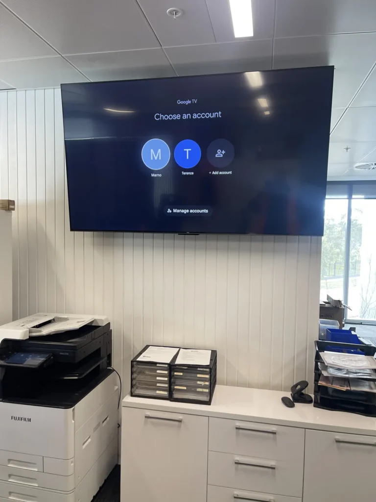 Large TV wall-mounted in an office above a storage unit