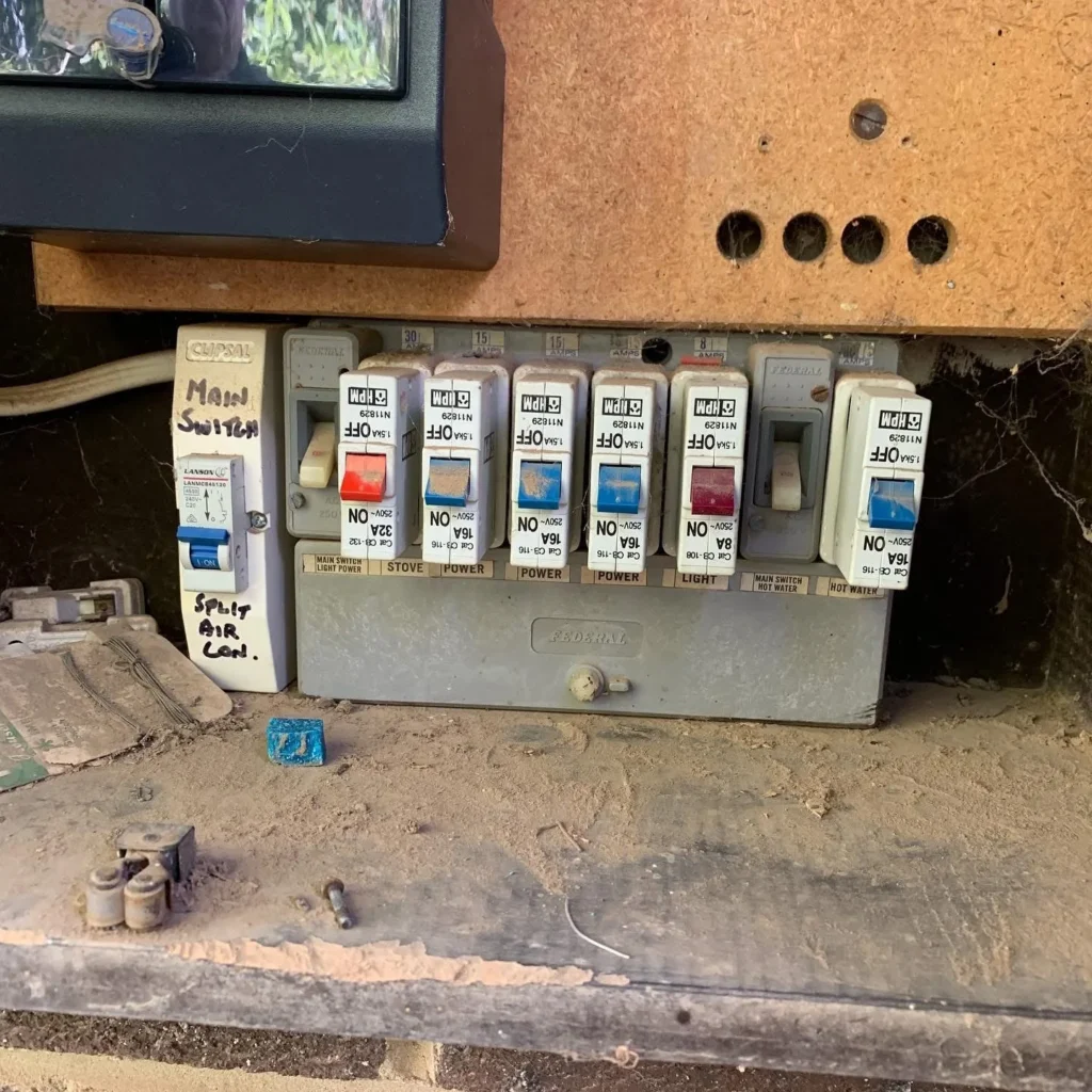 Older switchboard with plug-in breakers and a main switch before an upgrade